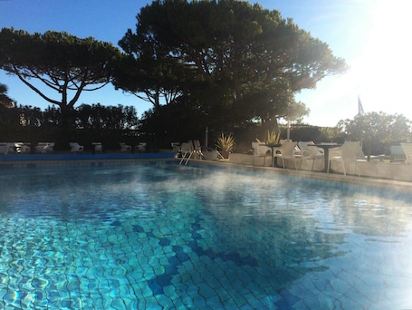 Una piscina al aire libre, sillones reclinables de piscina