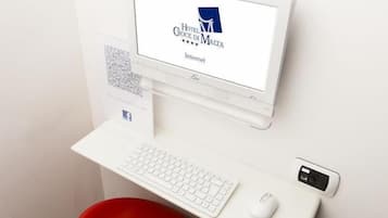 Una camera d'albergo con una scrivania, una tastiera, un mouse e un monitor del computer che mostra il logo dell'Hotel Croce di Malta.