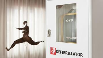 A defibrillator in a room with a curtain and a mannequin.