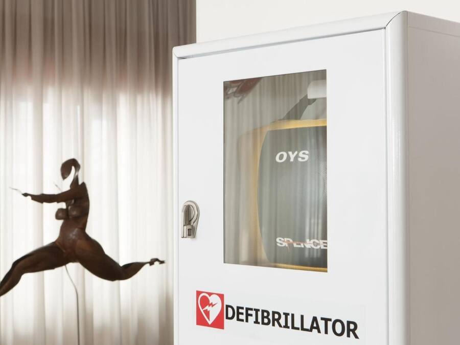 A defibrillator in a room with a curtain and a mannequin.