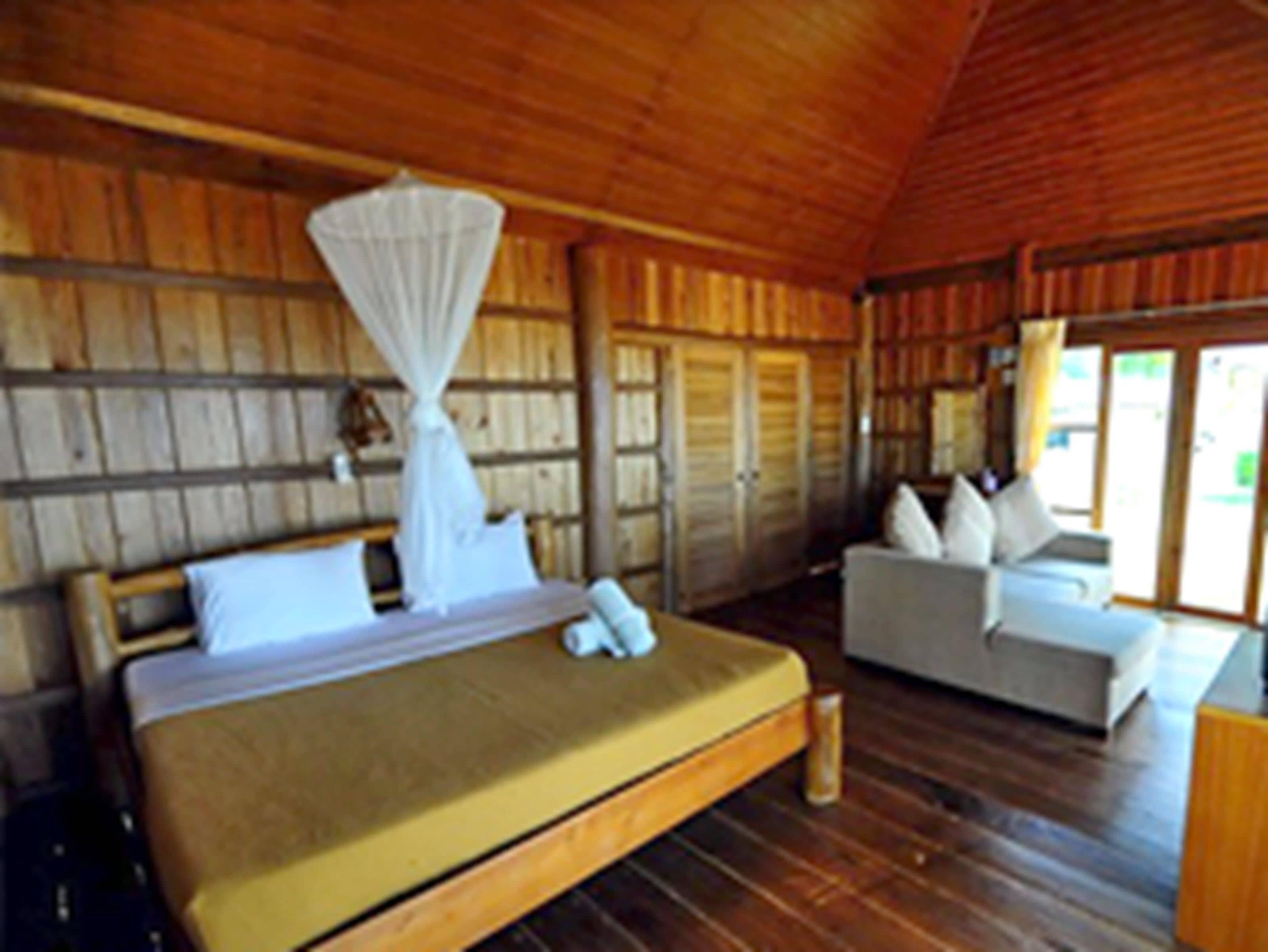 A wooden room with a bed and a sofa.