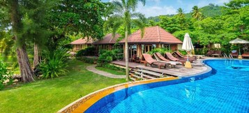 Un resort con piscina, sillas de descanso y un jardín tropical.