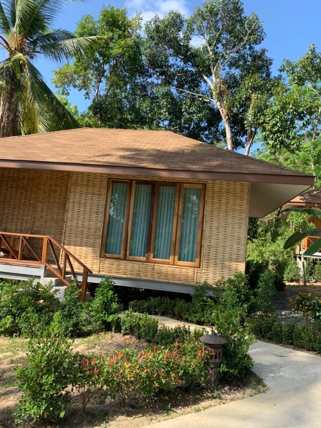 A bungalow with a tiled roof, large windows, and a wooden staircase leading to the entrance.