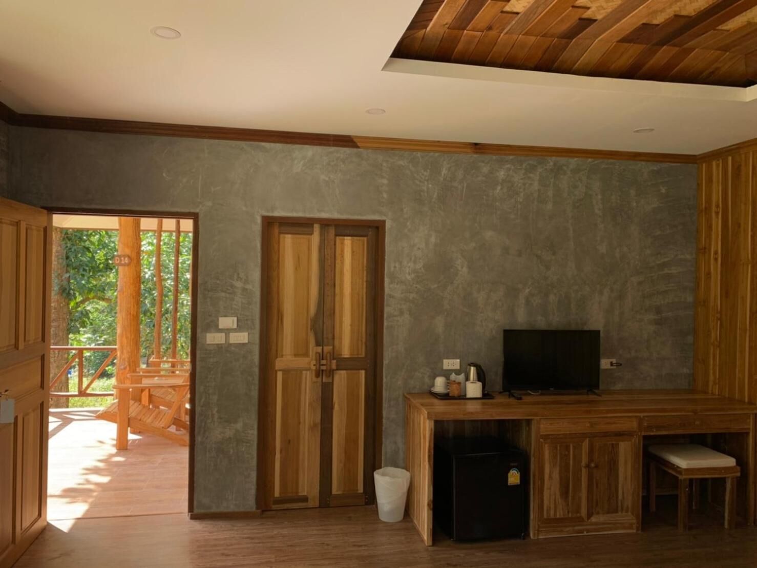 Una sala de estar moderna con un mueble de televisión de madera, un refrigerador pequeño negro y un banco de madera.