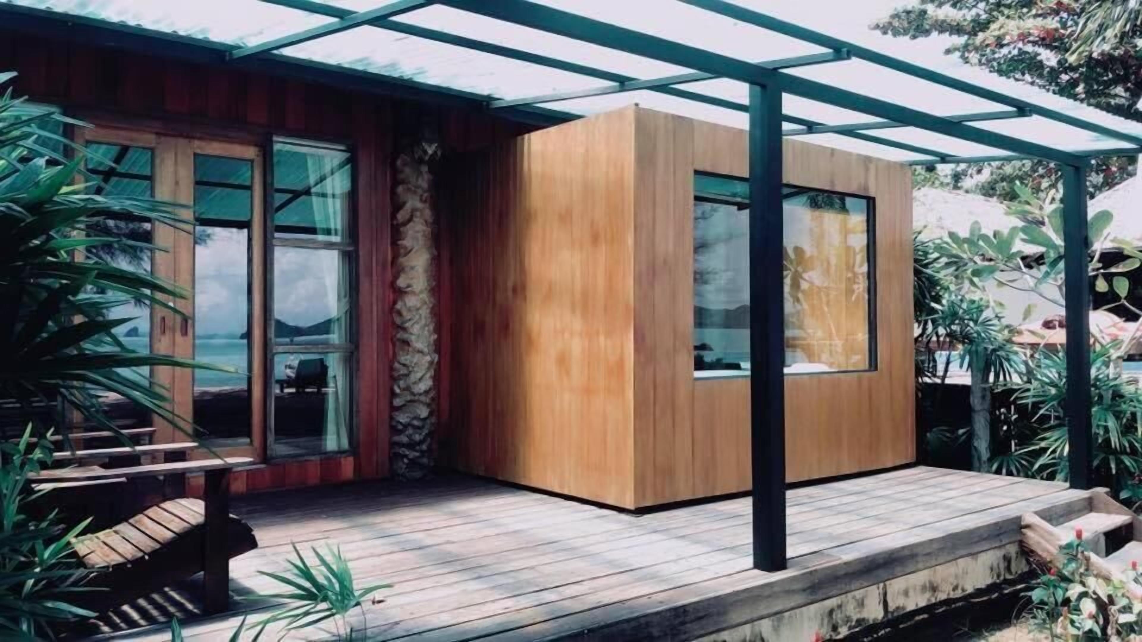 Una casa moderna con fachada de madera, ventanas grandes y un porche cubierto.