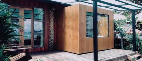 Una casa moderna con fachada de madera, ventanas grandes y un porche cubierto.