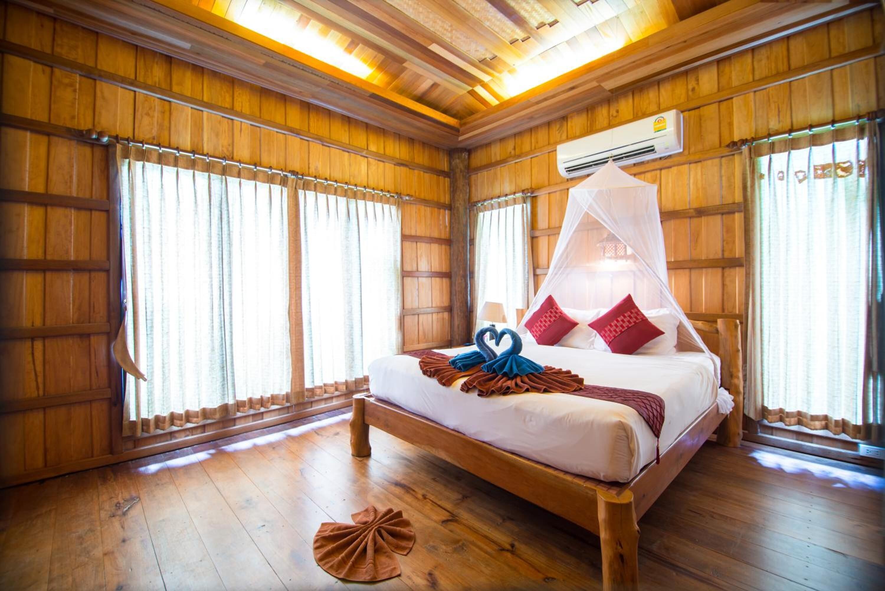 A wooden room with a bed, curtains, and an air conditioning unit.