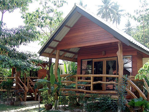 Una cabaña de madera con porche, rodeada de vegetación tropical.