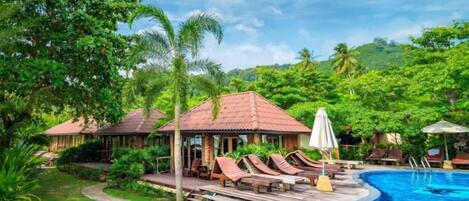 A resort with a swimming pool, lounge chairs, and a gazebo.