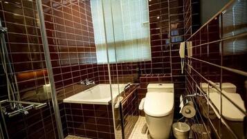 A bathroom with a glass-enclosed shower, a bathtub, a toilet, and a window with blinds.