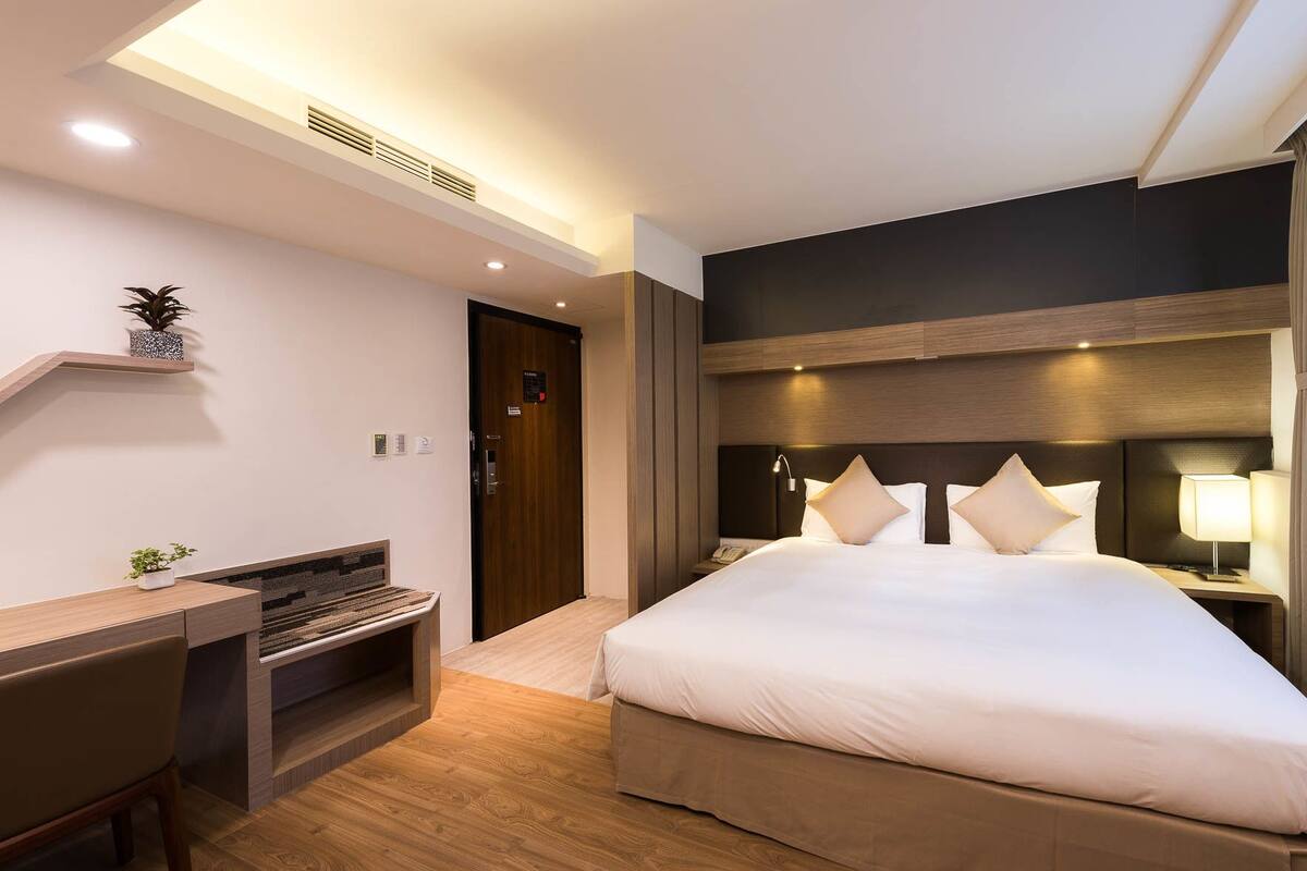 Une chambre d’hôtel moderne avec un grand lit, un bureau et une petite plante.