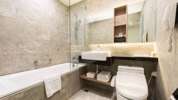 A modern bathroom with a bathtub, a sink, a toilet, and a glass-enclosed shower.