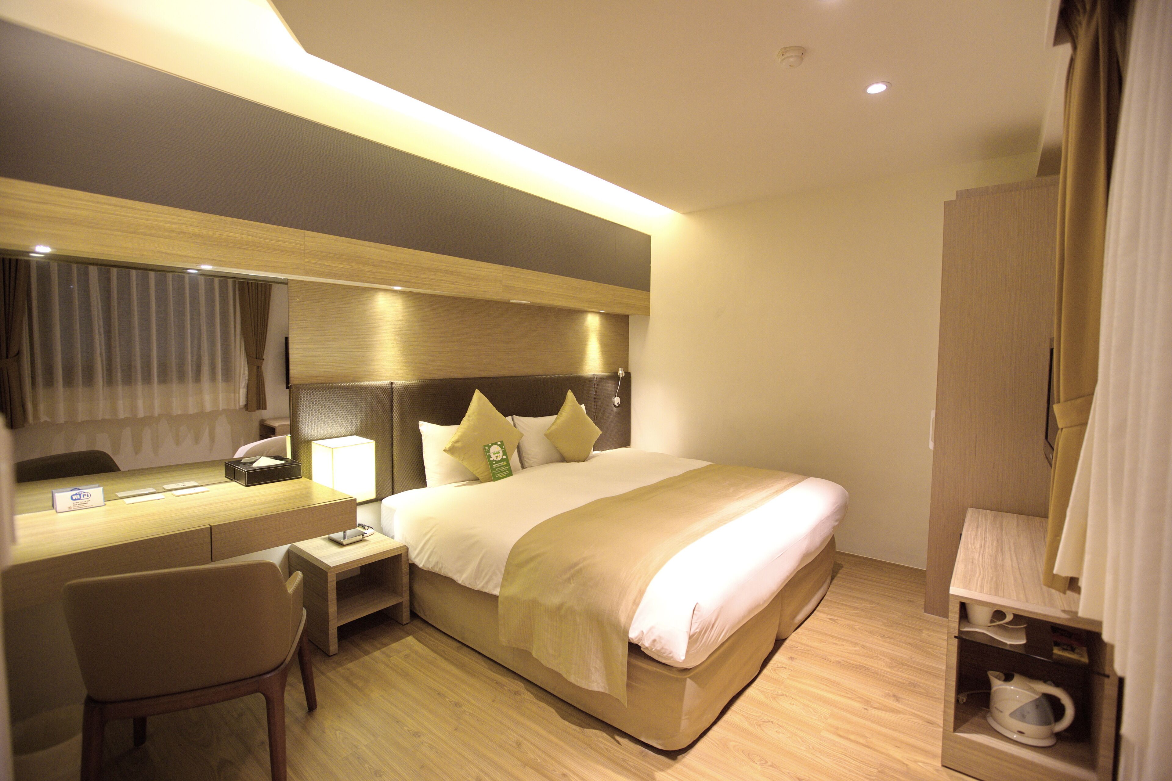 Una habitación de hotel con cama, mesita de noche, silla, escritorio y armario.
