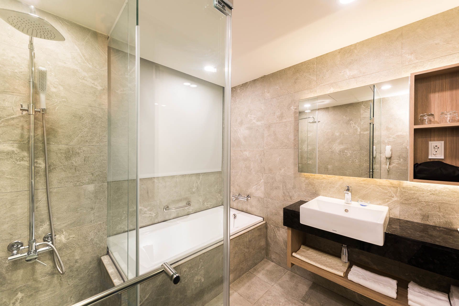 A modern bathroom with a glass-enclosed shower, a white sink, and a mirror above the sink.