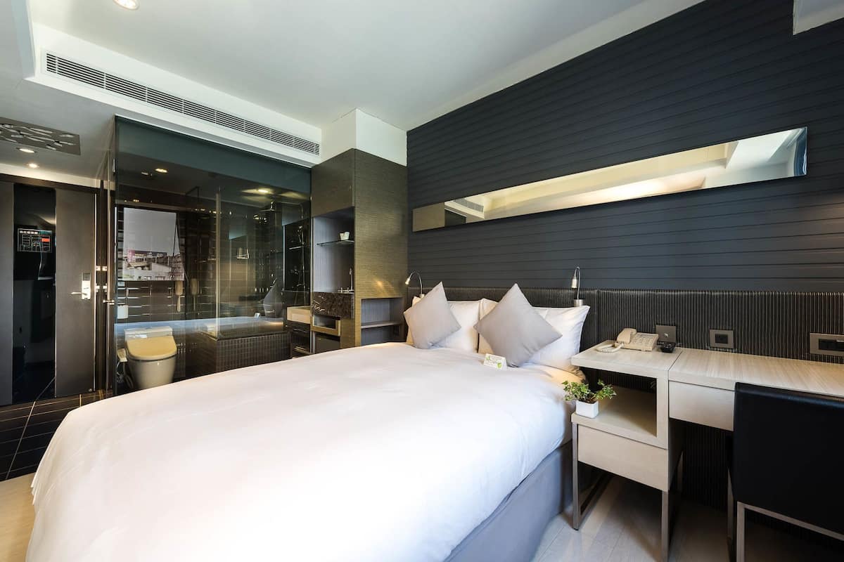 Une chambre d’hôtel moderne dotée d’un grand lit, d’un bureau et d’un espace douche.