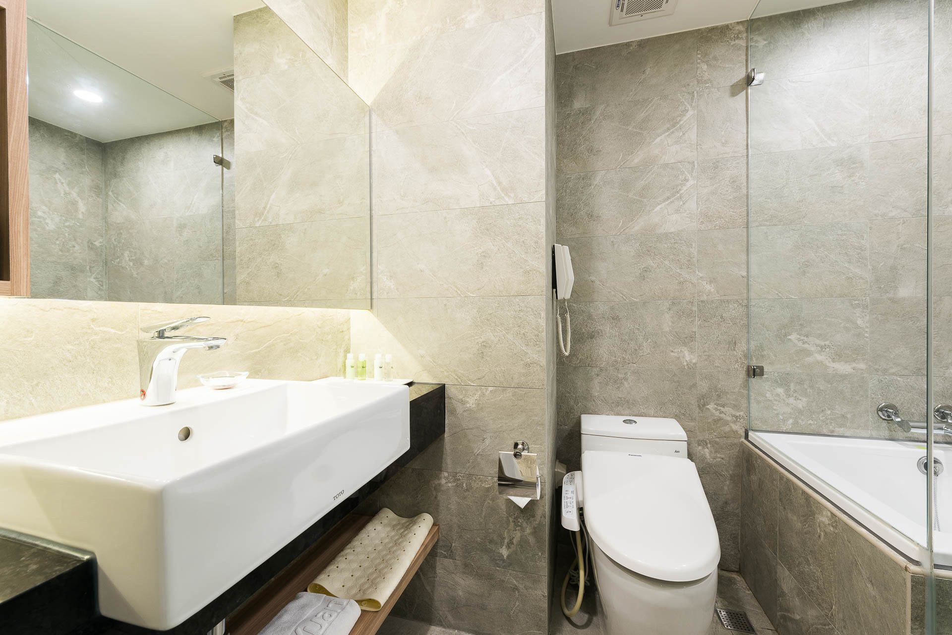A modern bathroom with a large sink, toilet, and shower area.