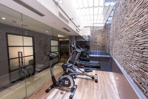 Un gimnasio moderno con equipo de ejercicio, paredes de vidrio y una pared de piedra.
