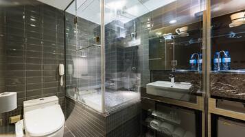 A modern bathroom with a glass-enclosed shower, a toilet, a sink, and a towel rack.