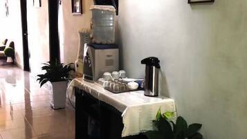 Un couloir avec un comptoir d’accueil, un distributeur d’eau, une machine à café et des tableaux encadrés accrochés au mur.