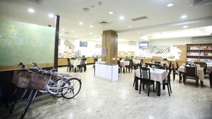 Un restaurant spacieux, doté de nombreuses tables et chaises, d’un pilier central et de présentoirs remplis de livres.