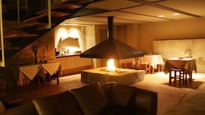 A cozy living area with a fireplace, a dining table, and a staircase. - Moinhos da Gozundeira - Casa no Campo (Sobral de Monte Agraco)