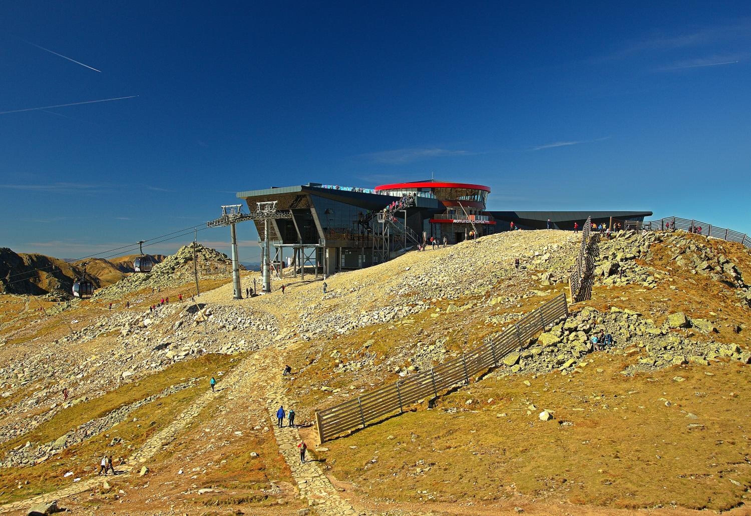 A ski resort with a red-roofed building, a ski lift, and a rocky terrain.