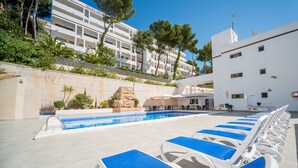 A poolside area with lounge chairs, a pool, and a building in the background. - Sun Beach (Calvia)