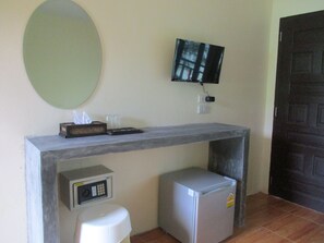 Una pequeña cocina americana equipada con microondas, refrigerador y televisor de pantalla plana montado en la pared.