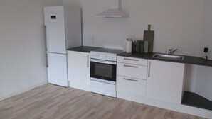 Een kleine keuken met een koelkast, oven en wastafel.