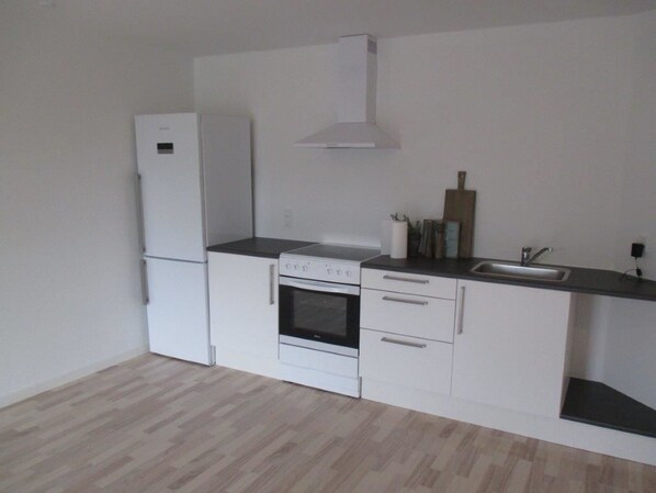 Una cocina compacta con refrigerador, horno y pileta.