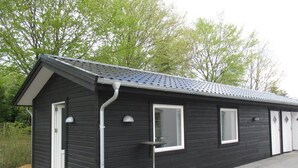 Een klein, donker gebouw met een schuin dak, een deur en een raam.