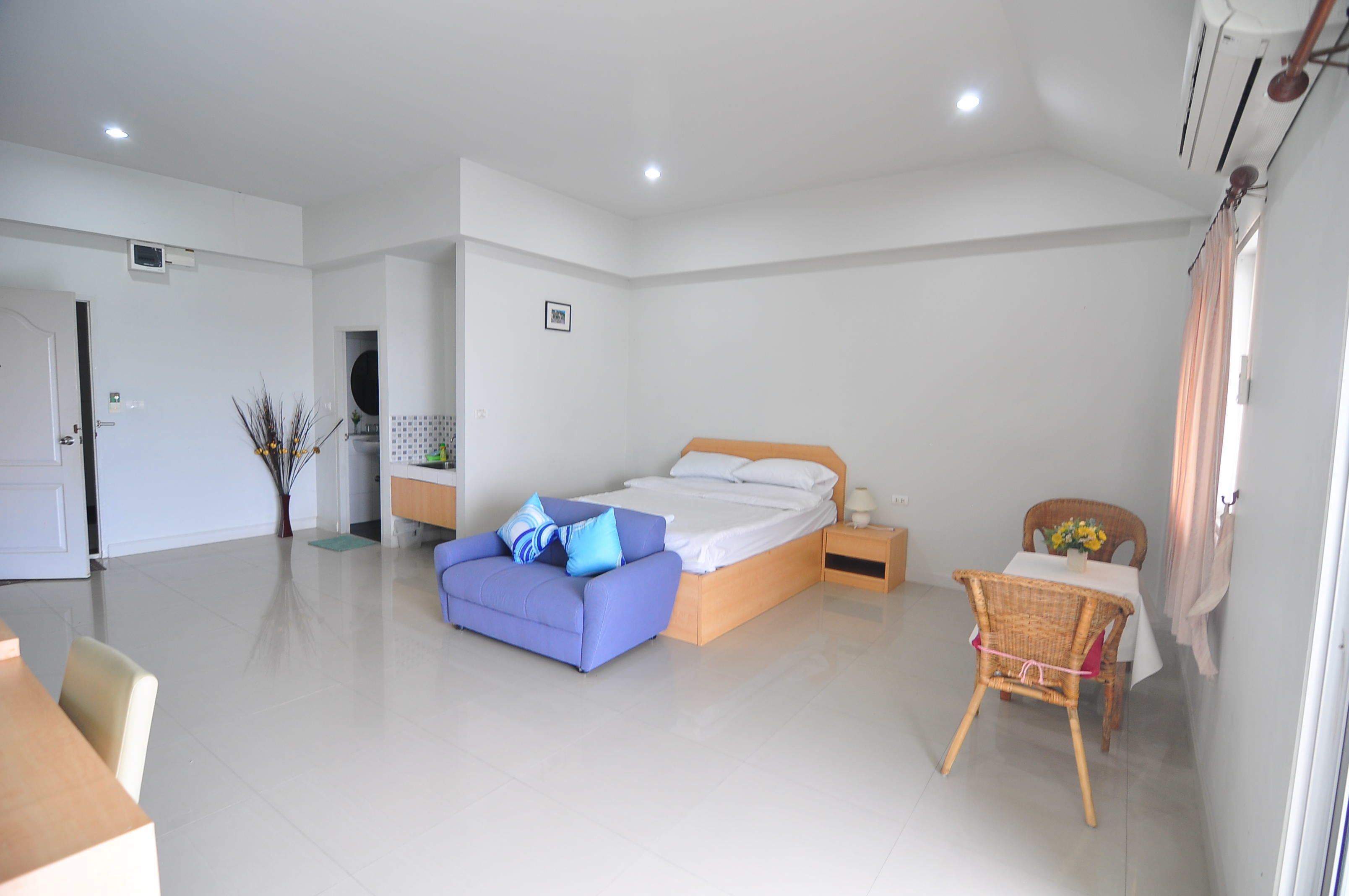 A modern bedroom with a large bed, a small table with a vase, and a chair.