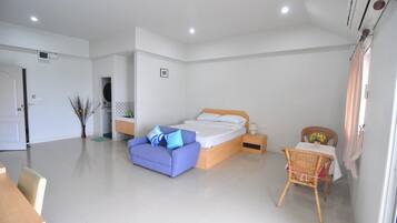 A modern bedroom with a large bed, a small table with a vase, and a chair.
