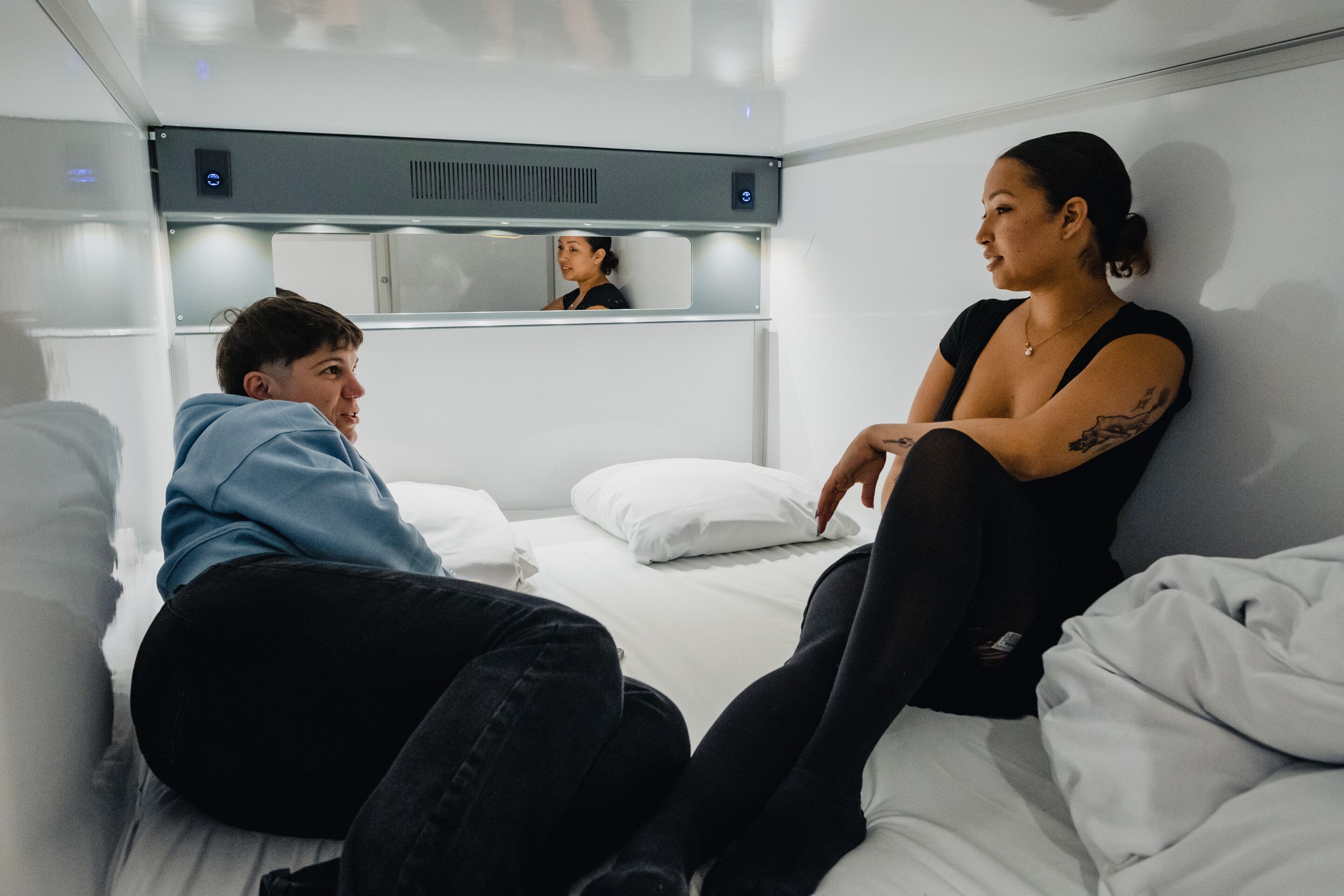 Una habitación de hotel moderna con una cama, una mesita de noche y un espejo.