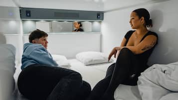 Una habitación de hotel moderna con una cama, una mesita de noche y un espejo.