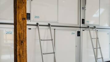 Een kamer met houten balken, witte kasten genummerd 202, 203, 204, 205 en 206, en twee metalen ladders die tegen de kasten leunen.