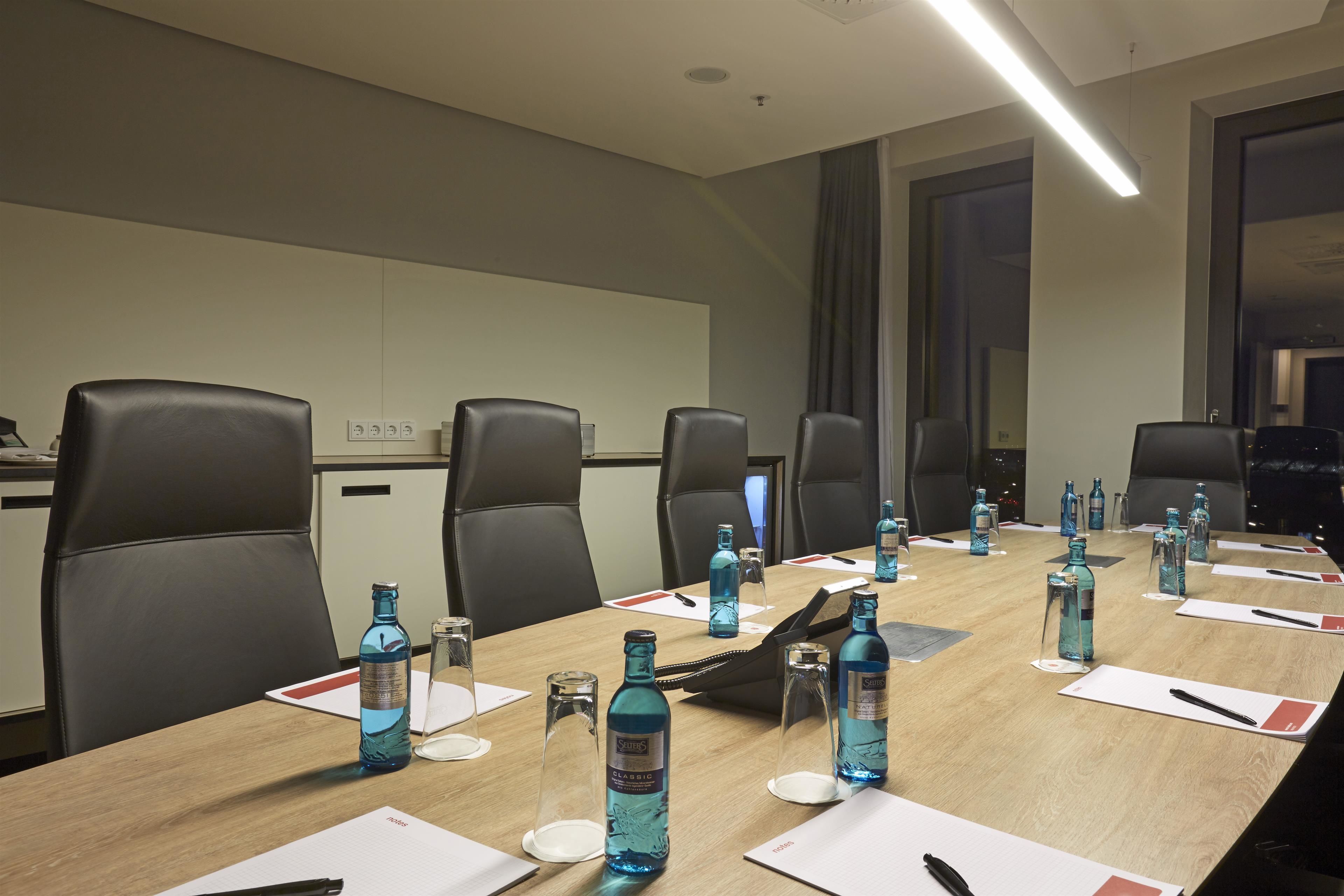 A conference room with a long table, multiple chairs, and water bottles.