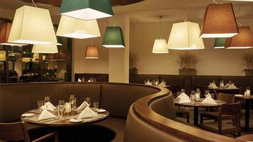 A restaurant with round tables set for dining, featuring a variety of pendant lights.