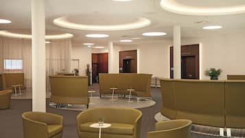 A modern lobby with a circular seating area, a reception desk, and a large window with curtains.