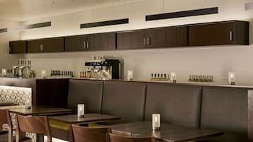 Un restaurante moderno con cabinas de madera oscura, una zona de bar con una máquina de café y botellas ordenadas en la barra.