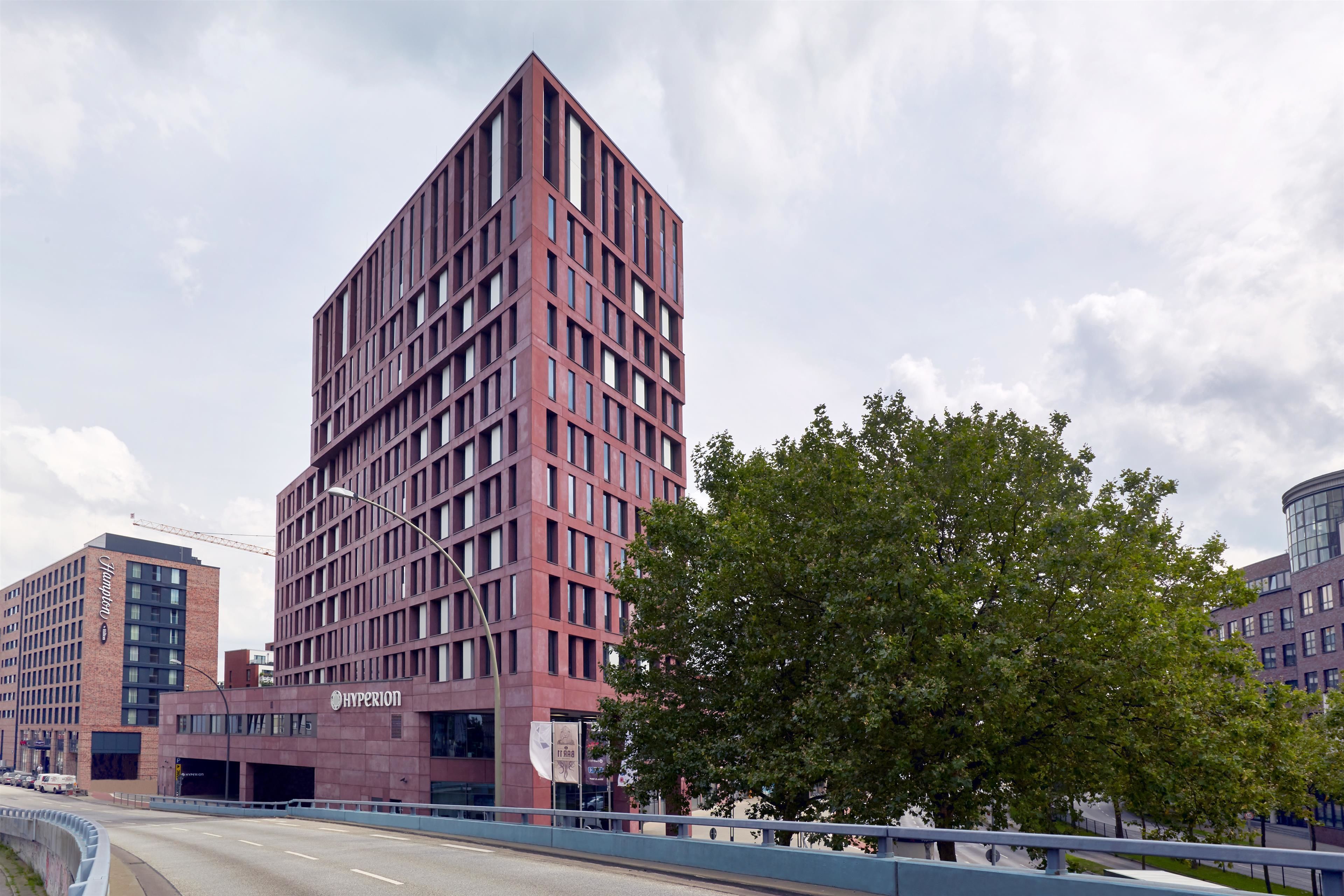 Un bâtiment moderne en briques rouges, doté de nombreuses fenêtres et d’une enseigne « Hyperion » bien visible.