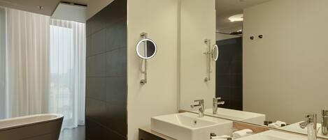 Un baño moderno con una bañera independiente, dos lavamanos y un espejo grande.