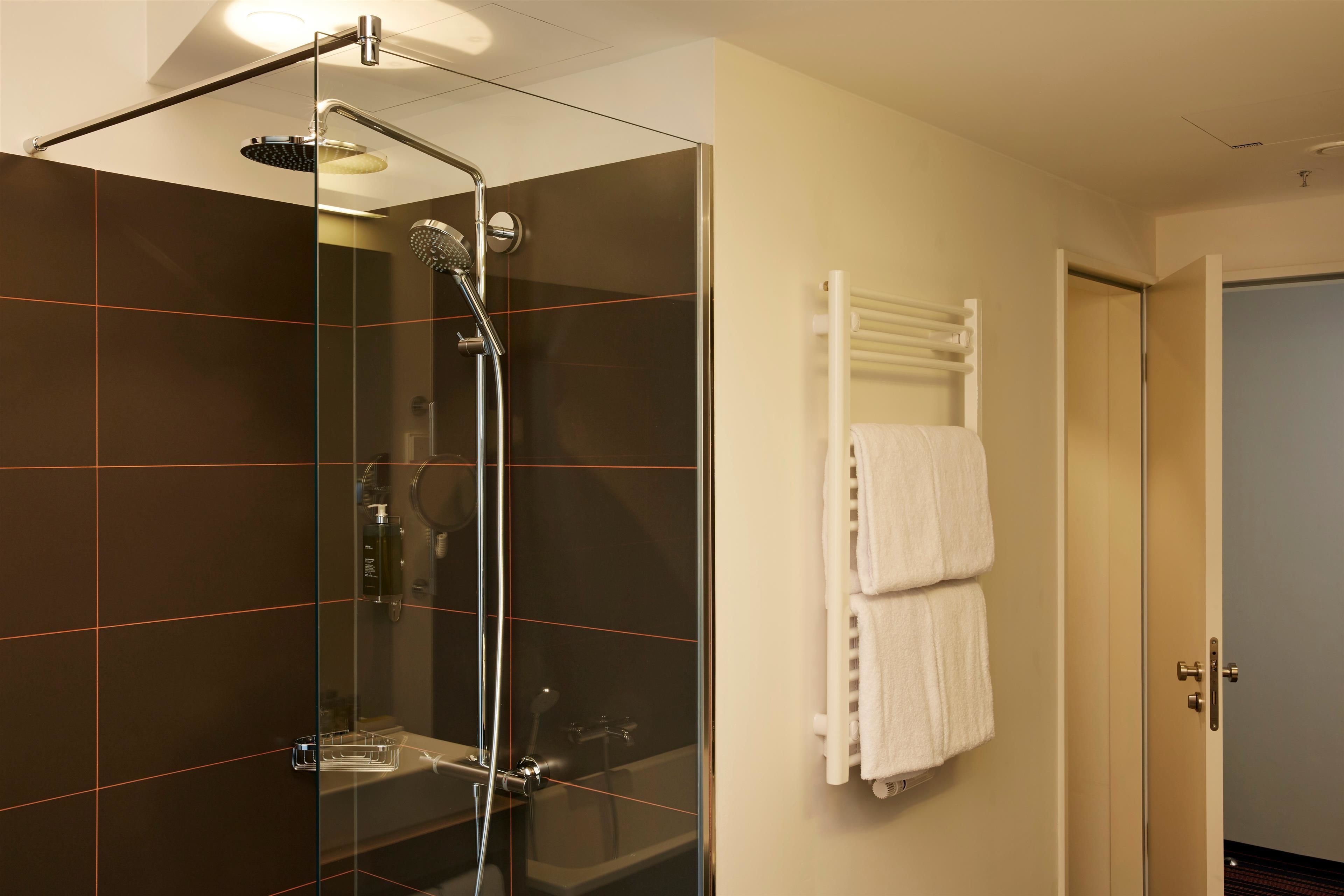 Un baño moderno con ducha acristalada, toallero blanco y puerta visible.