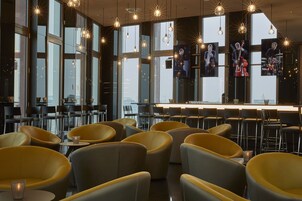 Ein modernes Restaurant mit gelben Stühlen, einer Bar und großen Fenstern.