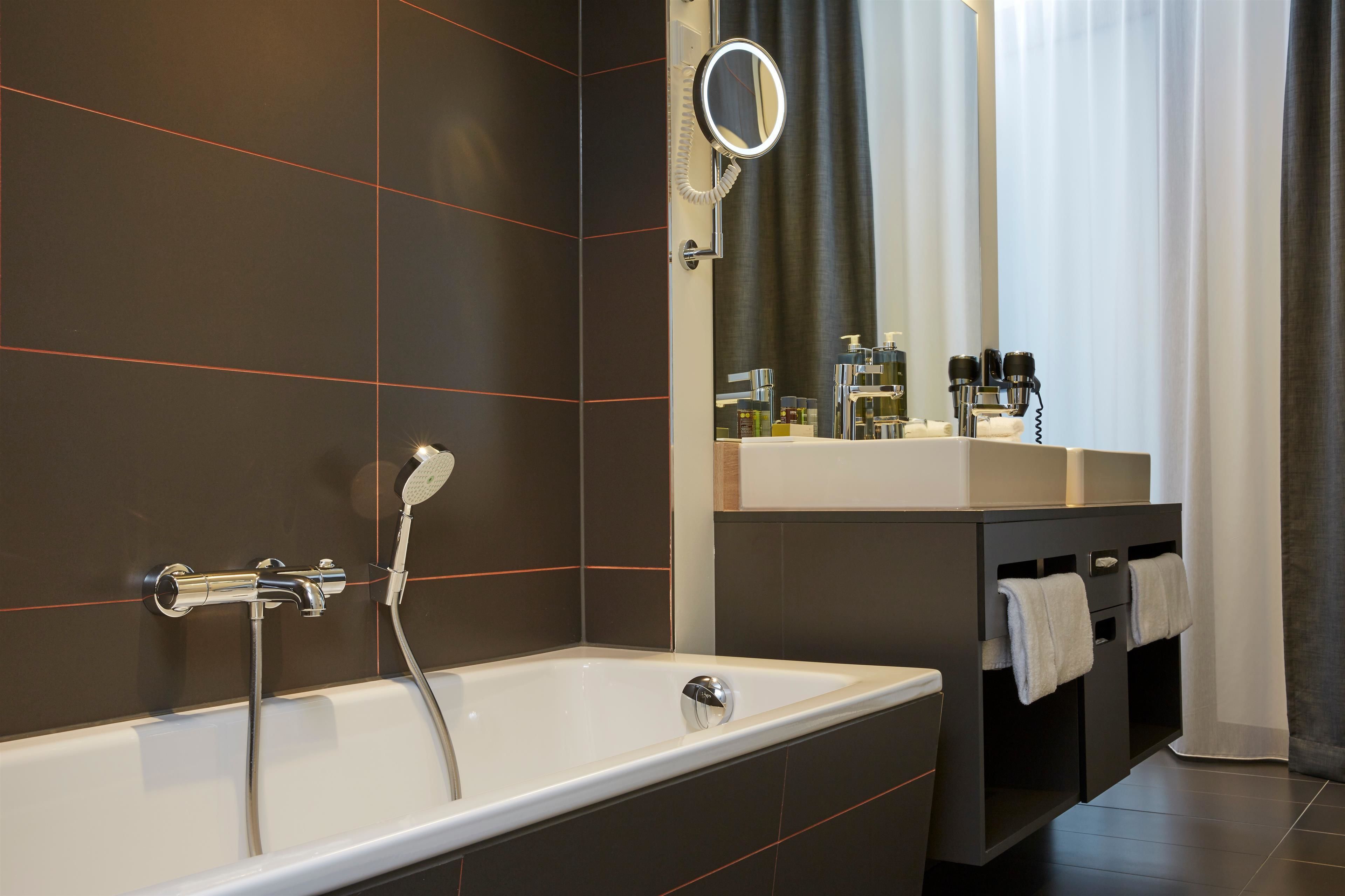 A modern bathroom with a bathtub, a vanity with a mirror, and a shower.