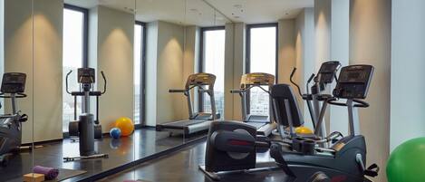 Un gimnasio con máquinas de cardio, pesas y pelotas de ejercicio.