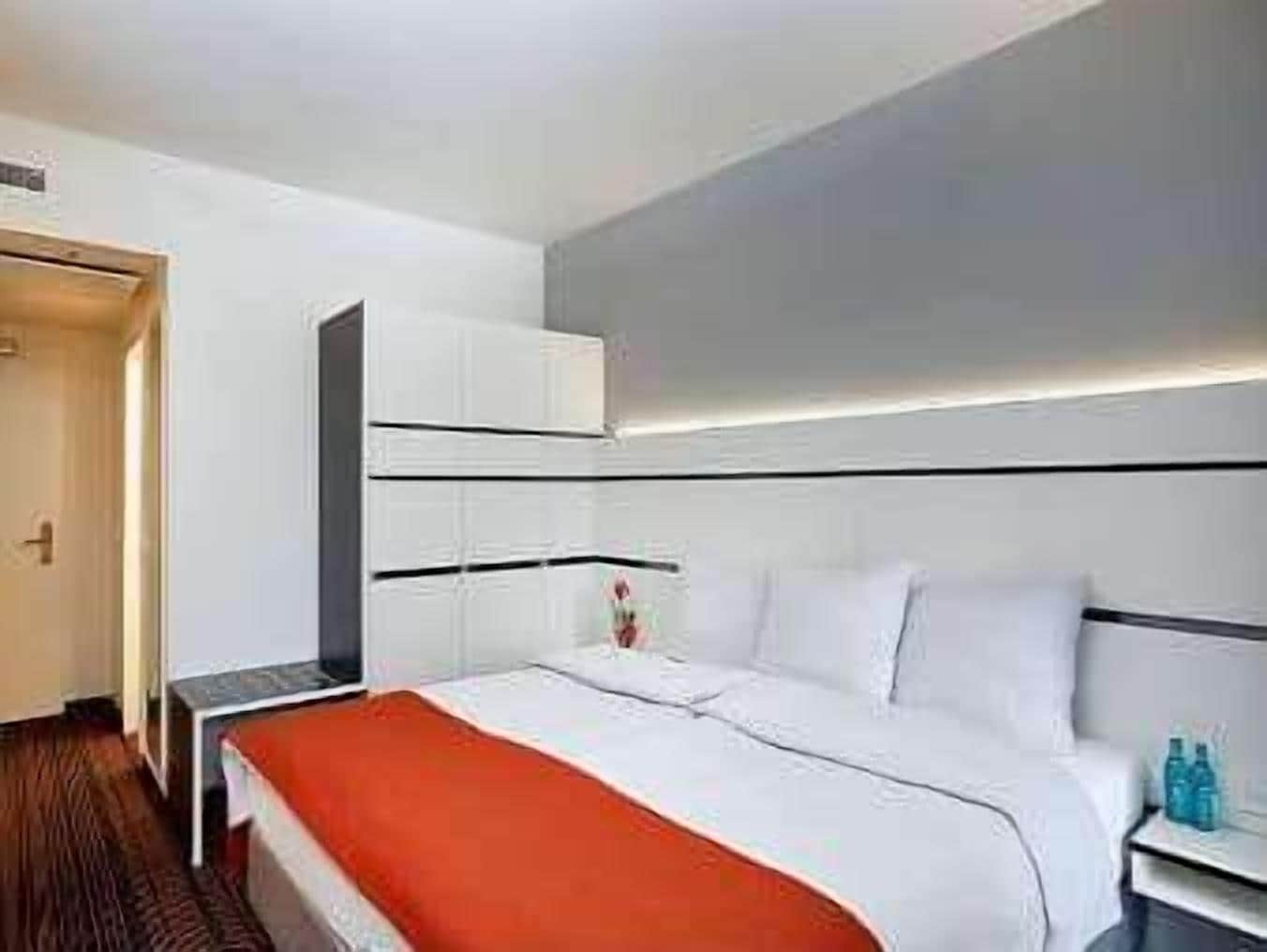 A hotel room with a bed, a nightstand, a wardrobe, and a door.