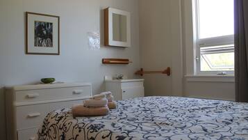 Un dormitorio con cama, cómoda, espejo y ventana.