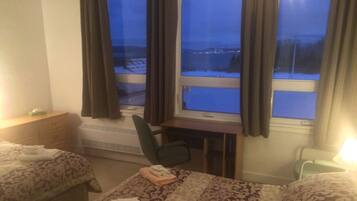 Habitación de hotel con dos camas, un escritorio y una silla. Se ve un paisaje nevado a través de la ventana.