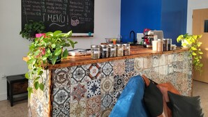 Una barra de café con un menú en pizarra, una máquina de café y varios frascos de especias.